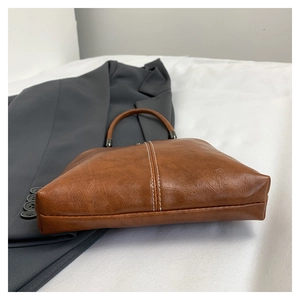 Close-up of vintage brown shell bag showing lychee grain texture and white stitching details