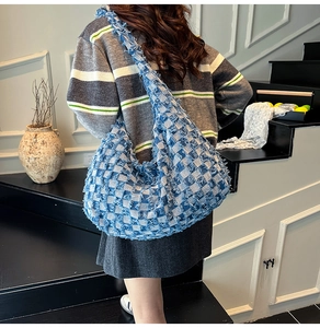 Detail of blue denim hobo bag featuring frayed tassel checkerboard design on shoulder