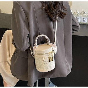 Detail of cream woven bucket bag with scarf handle on model in casual gray suit