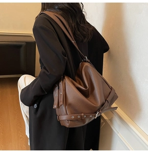 Brown lychee leather hobo bag featuring decorative metal eyelet straps on the side