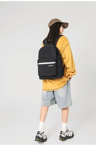Detailed back view of a black minimalist school backpack worn over a yellow sweatshirt