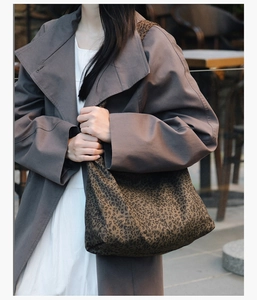 Gros plan sur un sac cabas léopard vintage avec un manteau gris et une robe blanche