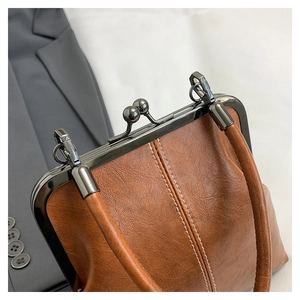 Close-up of brown vintage frame bag showing lychee grain texture and metal clasp