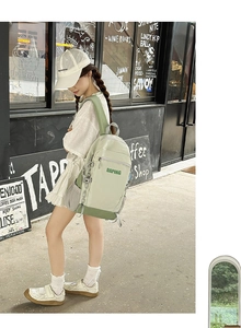 Detailed side view of the green and gray travel backpack worn outdoors by a model
