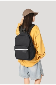 Detail shot of black minimalist backpack with front zipper pocket and white stripes
