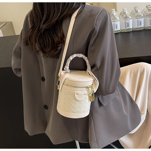 Detail of ivory PU leather bucket bag with woven pattern and silk scarf handle