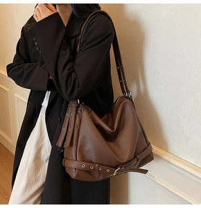 Brown litchi grain tote bag with decorative strap and adjustable shoulder strap on model