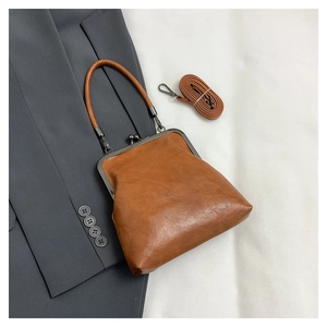 Retro tan shell bag with silver kiss-lock frame and adjustable strap on office blazer
