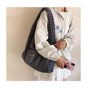 Detail shot of the side pocket on a large plaid canvas tote bag with leather label tag