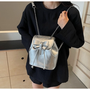 Detailed close-up of a silver metallic mini backpack with bow and chain strap detail