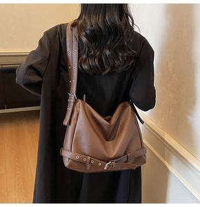 Close-up of brown pebbled leather shoulder bag with adjustable strap and metal eyelets