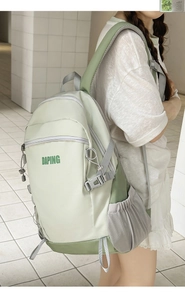 Detail of the mint green backpack showing ergonomic padded straps and side drawstring pocket
