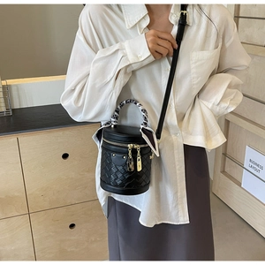 Detail of a black leather bucket bag with woven texture and a decorative scarf handle