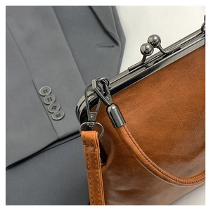 Close-up of vintage brown leather handbag with metallic ball lock and handle detail