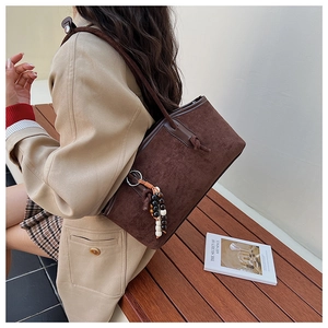 Detail der dunkelbraunen Wildleder-Tote-Bag mit Holzperlenquaste und eleganter Textur