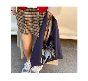 Detail of navy tote bag featuring light blue elephant print and side plaid ribbon bow