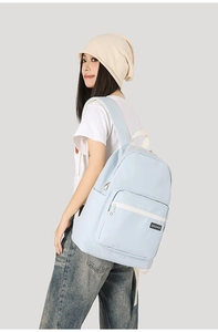 Detail shot of a light blue minimalist backpack showing the brand label and waterproof fabric