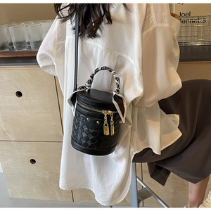 Detail of black woven bucket bag with silk scarf handle and golden lock charms
