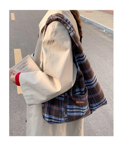 Detail of a large plaid tote bag in thick woven fabric with brown leather patch detail