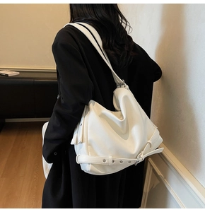 Detail of white pebbled leather tote bag with belt buckle accents and silver metal eyelets