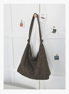 Détail d'un sac cabas en tissu imprimé léopard avec une bandoulière large et souple