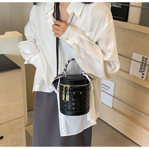 Macro shot of black woven bucket bag with silk scarf handle and golden zipper charms