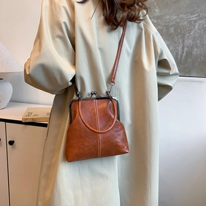 Detail of vintage brown leather shell bag with white stitching and metal frame clasp