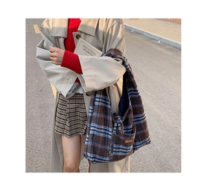 Detailed macro view of the checkered fabric texture and leather logo on a large tote bag