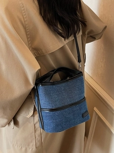 Blue denim bucket bag with black leather trim worn with a khaki trench coat