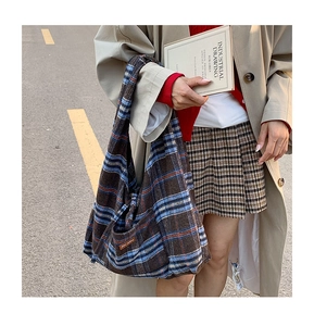 Detail of vintage plaid hobo bag with side pocket and brown leather patch in street view