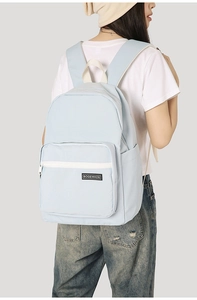 Close-up of light blue canvas backpack with white zippers and branded logo label