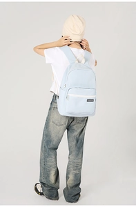 Rear view of a light blue minimalist backpack showing fit and shoulder straps