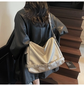 Detail of metallic champagne hobo bag with pebble leather texture and decorative buckles