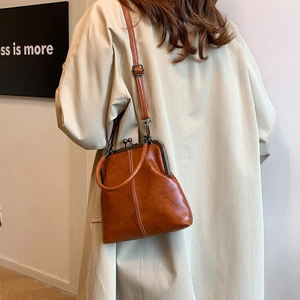 Detail of vintage brown kiss-lock crossbody bag with polished faux leather and metal clasp