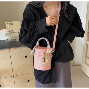 Close-up of pink cylinder bucket bag with woven texture and silk scarf handle detail