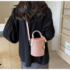 Detail of pink bucket bag with woven texture, decorative silk scarf, and metal lock charm