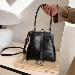 Detailed view of black retro shell bag with glossy pleated leather and silver clasp
