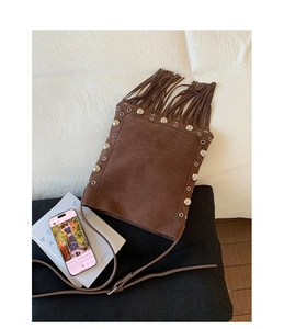 Detail of brown matte shoulder bag with stylish tassels and polished metal rivets