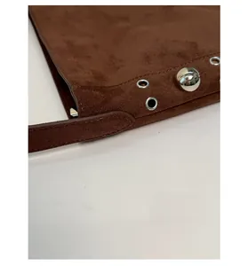 Macro detail of dark brown matte suede shoulder bag with silver rivets and metal eyelets