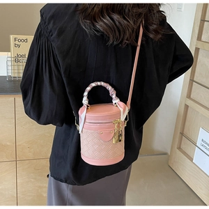 Pink woven leather bucket bag with silk scarf handle detail worn by a model