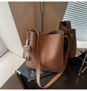 Brown litchi-grain leather bucket bag with shoulder strap and plush charm detail