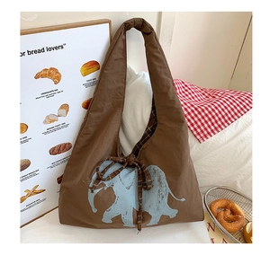 Detail of canvas tote with blue elephant print and brown plaid ribbon closure