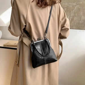 Detail of vintage black shell bag featuring shiny leather texture and metal frame clasp