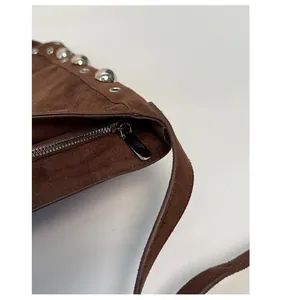Macro detail of dark brown suede shoulder bag with silver studs and smooth metal zipper