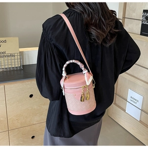 Detail of pink woven bucket bag with scarf-wrapped handle and golden lock charms