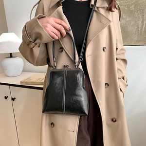Close-up of vintage black shell bag featuring classic metal clasp and fine leather texture