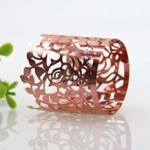 Close-up of laser-cut rose gold napkin ring featuring intricate hollow rose patterns