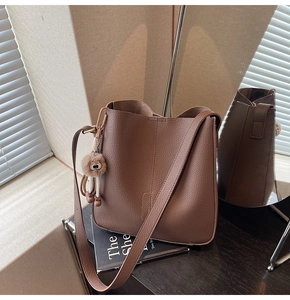 Detail of lychee pattern brown leather bucket bag with cute owl plush charm
