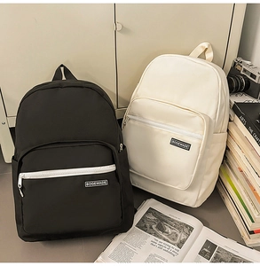 Minimalist canvas backpacks in black and beige displayed with vintage books and camera