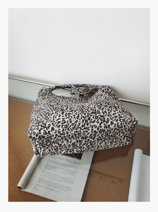 Détail du grand sac cabas en toile à motif léopard avec poignée intégrée sur une table chic
